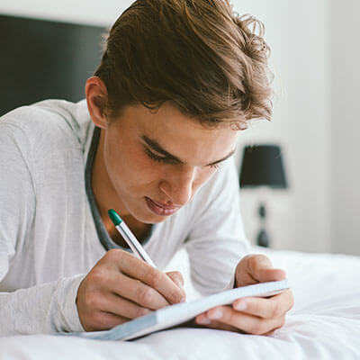 Teenage boy writing in his journal, practicing coping techniques he learned in depression therapy