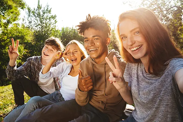 Smiling teenager surrounded by a supportive group of friends, illustrating the positive impact of healthy social connections in therapy outcomes