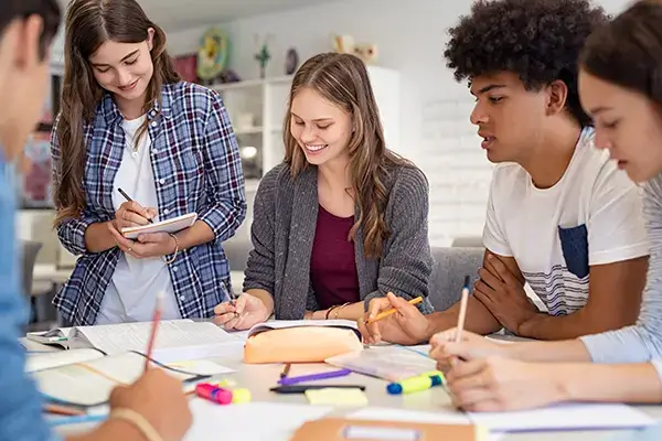 Smiling teenage girl collaborating with classmates on a school project in Thousand Oaks, CA, illustrating improved social skills and academic engagement through effective teen therapy
